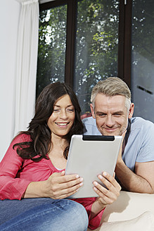 Deutschland, Berlin, Älteres Paar mit digitalem Tablet, lächelnd - SKF001120