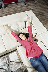 Germany, Berlin, Mature woman lying on sofa, smiling - SKF001125
