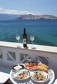 Croatia, Table laid with food in restaurant, adriatic sea in background at Baska - WWF002536