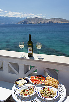 Kroatien, Gedeckter Tisch im Restaurant, im Hintergrund das adriatische Meer bei Baska - WWF002536