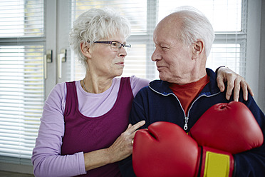 Germany, Duesseldorf, Senior couple with boxing glove, smiling - STKF000083