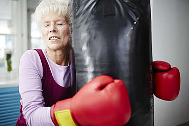 Germany, Duesseldorf, Senior woman with boxing glove and punch bag - STKF000088