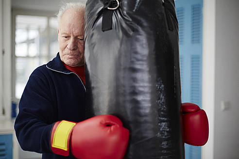 Germany, Duesseldorf, Senior man with boxing glove and punch bag - STKF000090