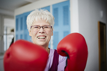 Germany, Duesseldorf, Portrait of senior woman with boxing glove, smiling - STKF000095