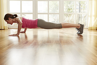 Germany, Duesseldorf, Mature woman doing push ups at home - STKF000111