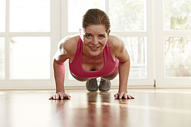 Germany, Duesseldorf, Mature woman doing push ups at home - STKF000113