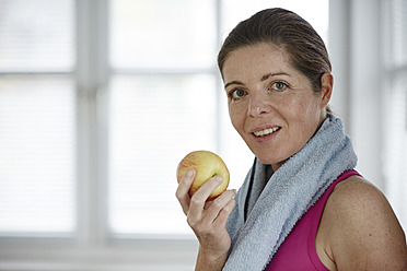 Germany, Duesseldorf, Mature woman eating apple, smiling - STKF000139
