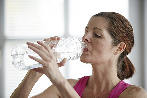 Germany, Duesseldorf, Mature woman drinking water after exercise - STKF000147