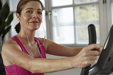 Germany, Duesseldorf, Mature woman exercising with treadmill, smiling portrait - STKF000152