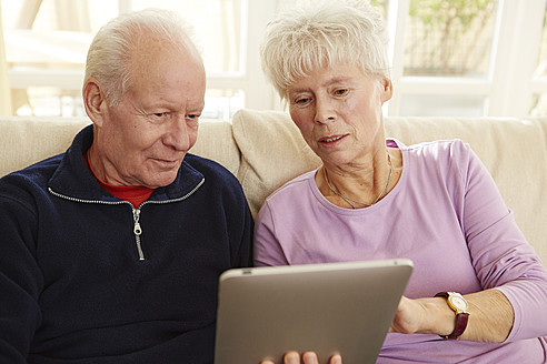 Deutschland, Düsseldorf, Älteres Ehepaar nutzt digitales Tablet und entspannt sich zu Hause - STKF000187