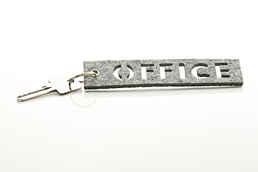 Nahaufnahme eines Büroschlüssels mit Schlüsselanhänger auf weißem Hintergrund - MAEF005343