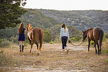 USA, Texas, Schwestern gehen mit Quarterhorses in der Nähe von Bergen spazieren - ABAF000549