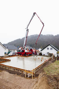 Europa, Deutschland, Rheinland-Pfalz, Bauarbeiter beim Einfüllen von Beton in eine Verschalung für ein Fundament - CSF016008