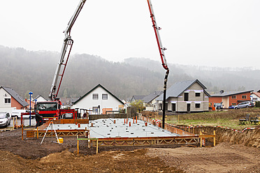 Europa, Deutschland, Rheinland-Pfalz, Bauarbeiter beim Einfüllen von Beton in eine Verschalung für ein Fundament - CSF016009