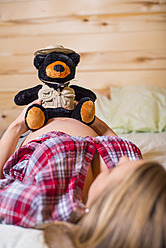 USA, Texas, Schwangere junge Frau mit Teddybär auf dem Bauch - ABAF000493