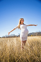 USA, Texas, Pregnant young woman stretching arms, smiling - ABAF000522