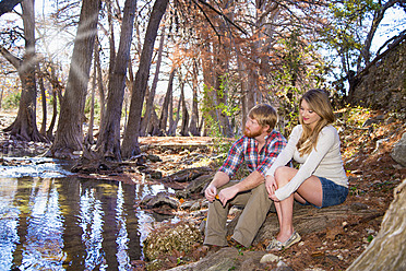 USA, Texas, Husband and wife sitting on creek - ABAF000534