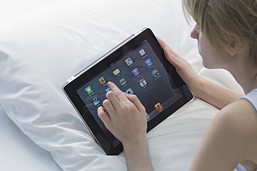 Deutschland, Junge Frau mit digitalem Tablet im Bett liegend - CRF002236