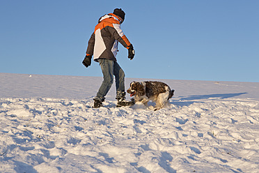 Germany, Bavaria, English Springer Spaniel and dog owner playing in snow - MAEF005447