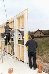 Europe, Germany, Rhineland Palantinate, Men installing and fixing wooden walls of prefabricated house - CSF016032