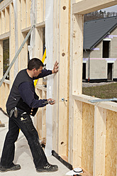 Europe, Germany, Rhineland Palatinate, Man installing and fixing wooden walls of prefabricated house - CSF016038