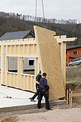 Europe, Germany, Rhineland Palantinate, Men installing and fixing wooden walls of prefabricated house - CSF016043