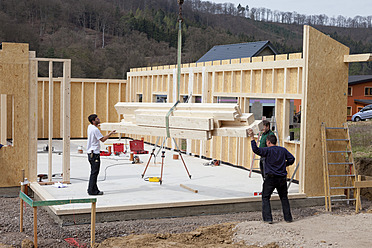 Europe, Germany, Rhineland Palantinate, Men installing and fixing wooden walls of prefabricated house - CSF016014