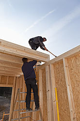 Europe, Germany, Rhineland Palantinate, Men installing and fixing wooden walls of prefabricated house - CSF016056
