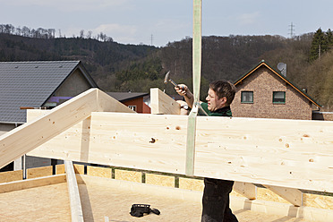 Europe, Germany, Rhineland Palantinate, Man assembling ridge purlin - CSF016062