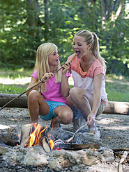 Austria, Friends preparing barbecue on camp fire - WWF002727