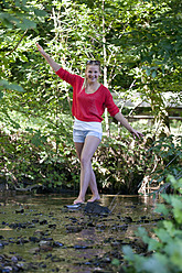 Austria, Teenage girl balancing on rock at stream - WWF002735