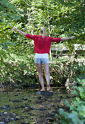 Austria, Teenage girl balancing on rock at stream - WWF002736