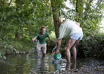 Österreich, Jugendliches Mädchen und Junge spritzen Wasser im Bach - WWF002744