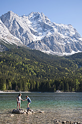 Germany, Bavaria, Boy and girl playing on Lake Eibsee with Zugspitze mountain in background - UMF000573