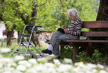 Österreich, Ältere Frau sitzt auf einer Bank und liest ein Buch - WWF002458