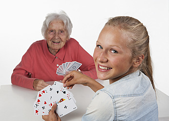 Senior woman and teenage girl playing cards, smiling - WWF002495