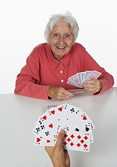 Senior woman and teenage girl playing cards, smiling - WWF002496