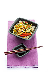 Chinese food in bowl with chopsticks and soy sauce placed on napkin - MAEF005505