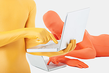 Männer in gelben und orangefarbenen Zentai mit Laptop - TCF003130