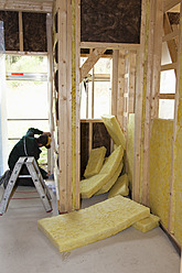 Europe, Germany, Rhineland Palatinate, Worker placing thermal felt insulation inside house - CSF016115