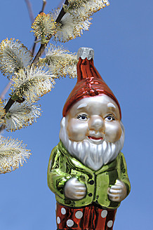 Garden gnome hanging on willow twig against blue background - HSTF000026