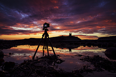 Großbritannien, England, DSLR-Kamera mit Stativ und Dunstanburgh Castle im Hintergrund - SMAF000048
