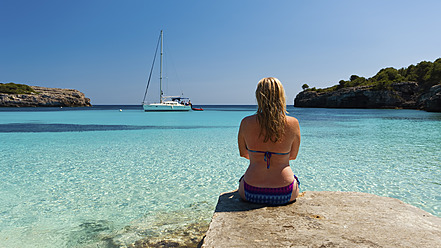 Spanien, Menorca, Frau sitzt am Steg in Cala Turqueta - SMAF000057