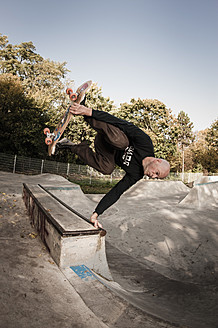 Germany, North Rhine Westphalia, Duesseldorf, Mature man jumping with skateboard - KJF000179
