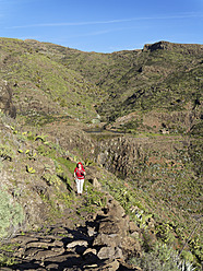 Spanien, La Gomera, Ältere Frau wandert durch den Barranco de Charco Hondo - SIEF003162