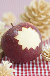 Apfel mit geschnitztem Stern und Tannenzapfen auf dem Tisch - ASF004738