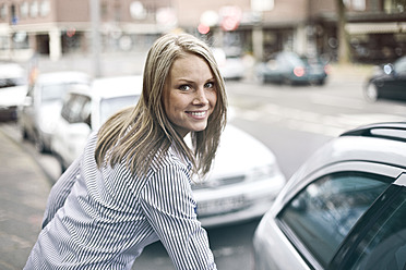 Germany, Duesseldorf, Young woman getting in to car, smiling, portrait - MF000457