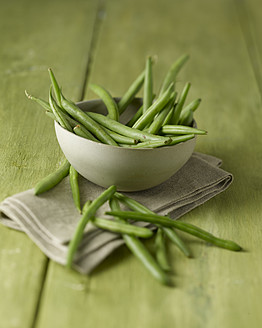 Bowl of green beans on wooden table, close up - KSWF001017