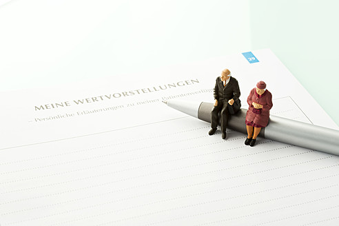 Figurines sitting on pen with advance directive form, close up - MAEF005546