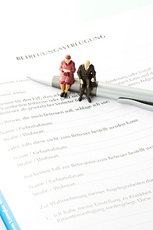 Figurines sitting on pen with advance directive form, close up - MAEF005553